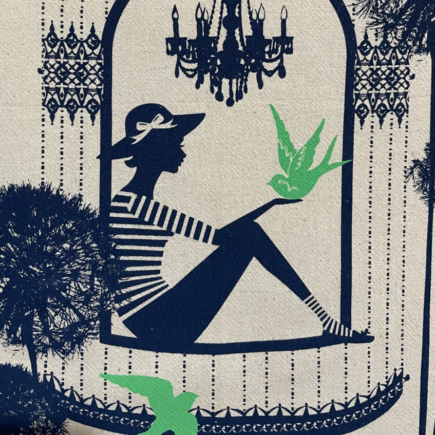 Closeup of colorful cotton tea towel with birds and a woman in a birdcage
