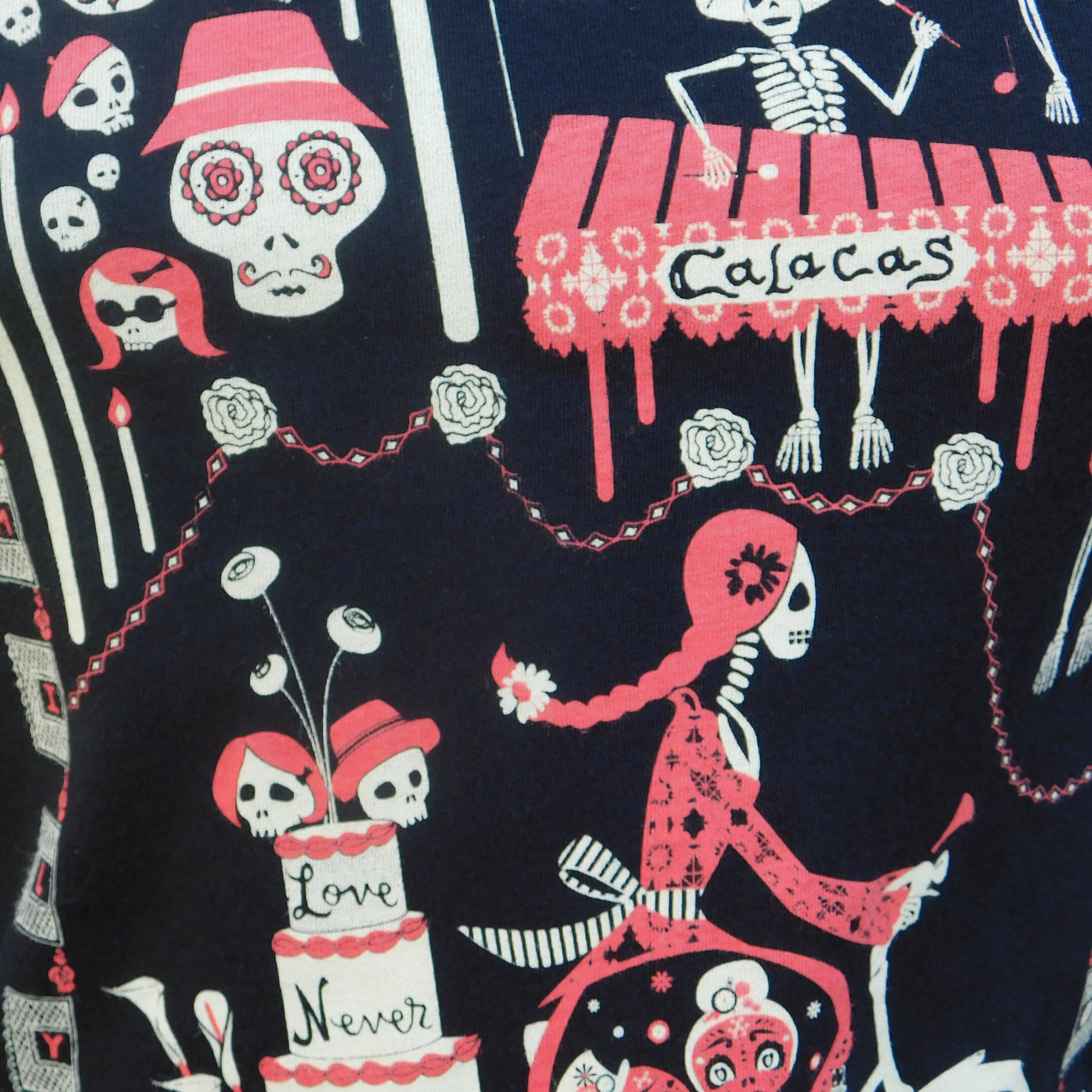 Closeup of fabric featuring graphic of skeletons celebrating and riding bikes