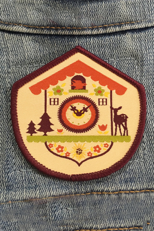 Purple, lime, yellow and red woven patch with a Bavarian cuckoo clock and purple border