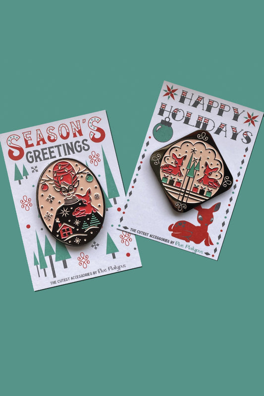 Two bright vintage inspired red and green enamel pins, one of masked woman with beehive hair and one with 2 reindeer