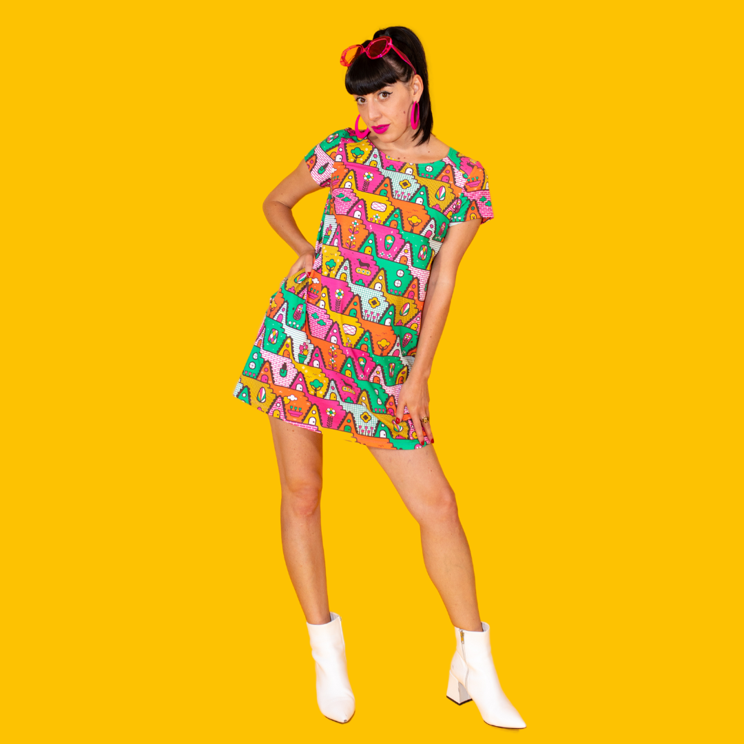 Dark-haired model in bright multicolored geometric pocket tunic with ankle boots, with hand on hip