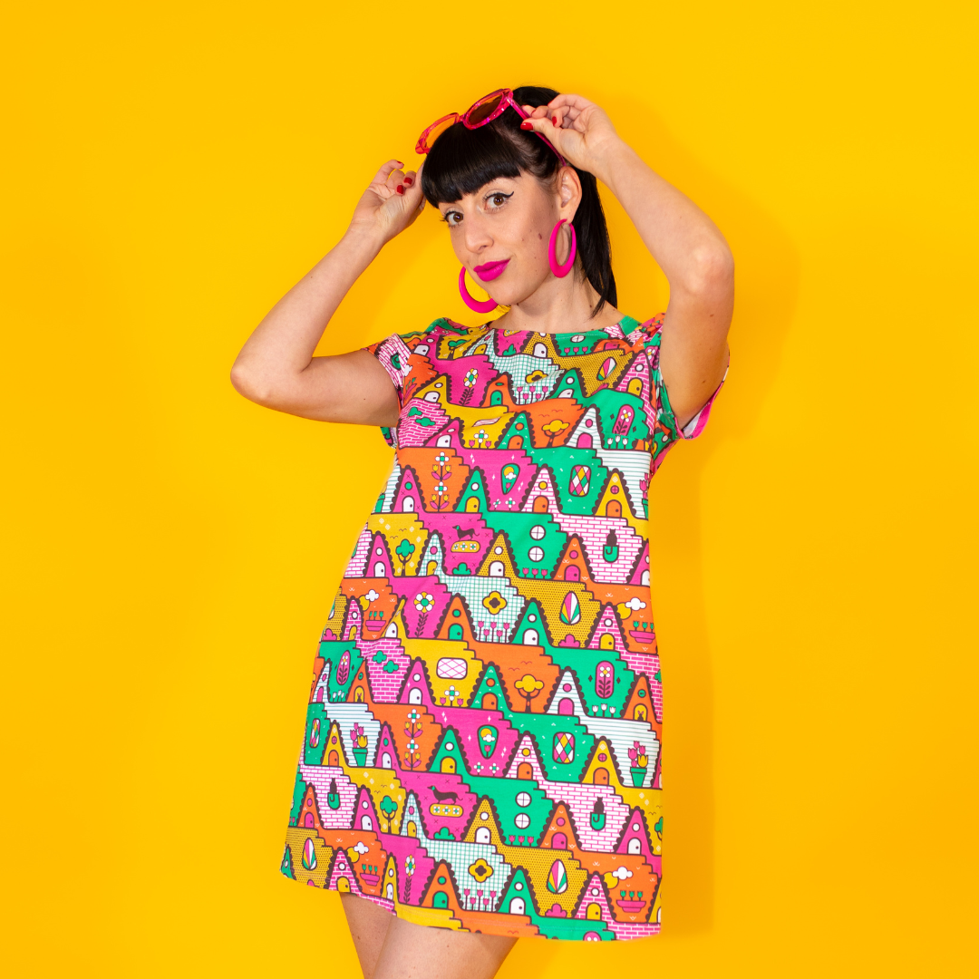 Closeup of dark-haired model in bright multicolored geometric pocket tunic with ankle boots