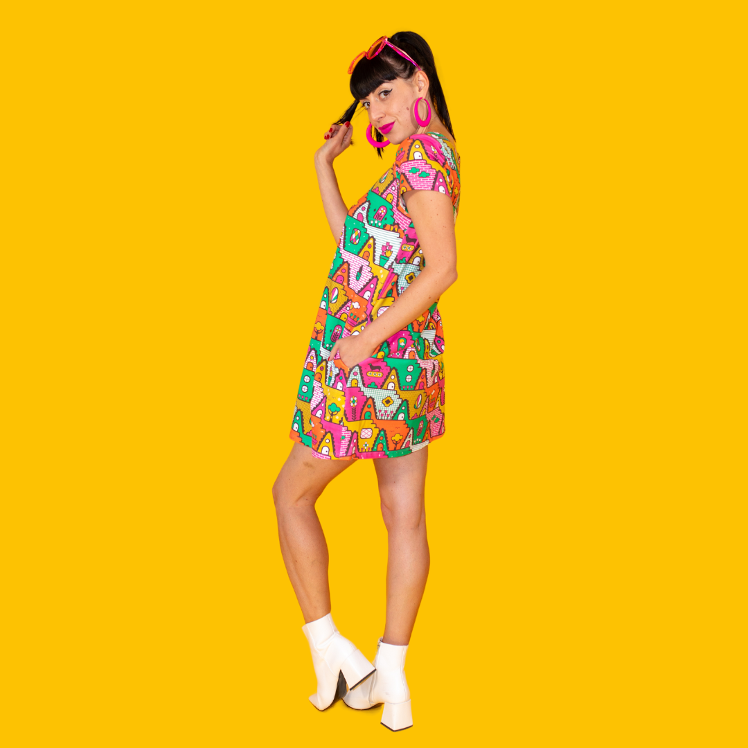 Side view of dark-haired model in bright multicolored geometric pocket tunic with ankle boots