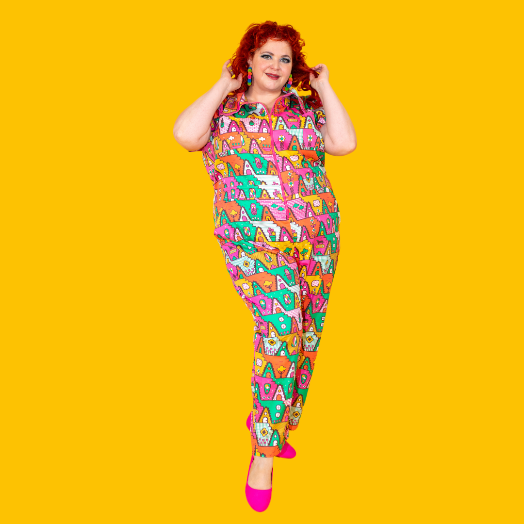 Red-haired model in bright geometric print jumpsuit and hot pink shoes