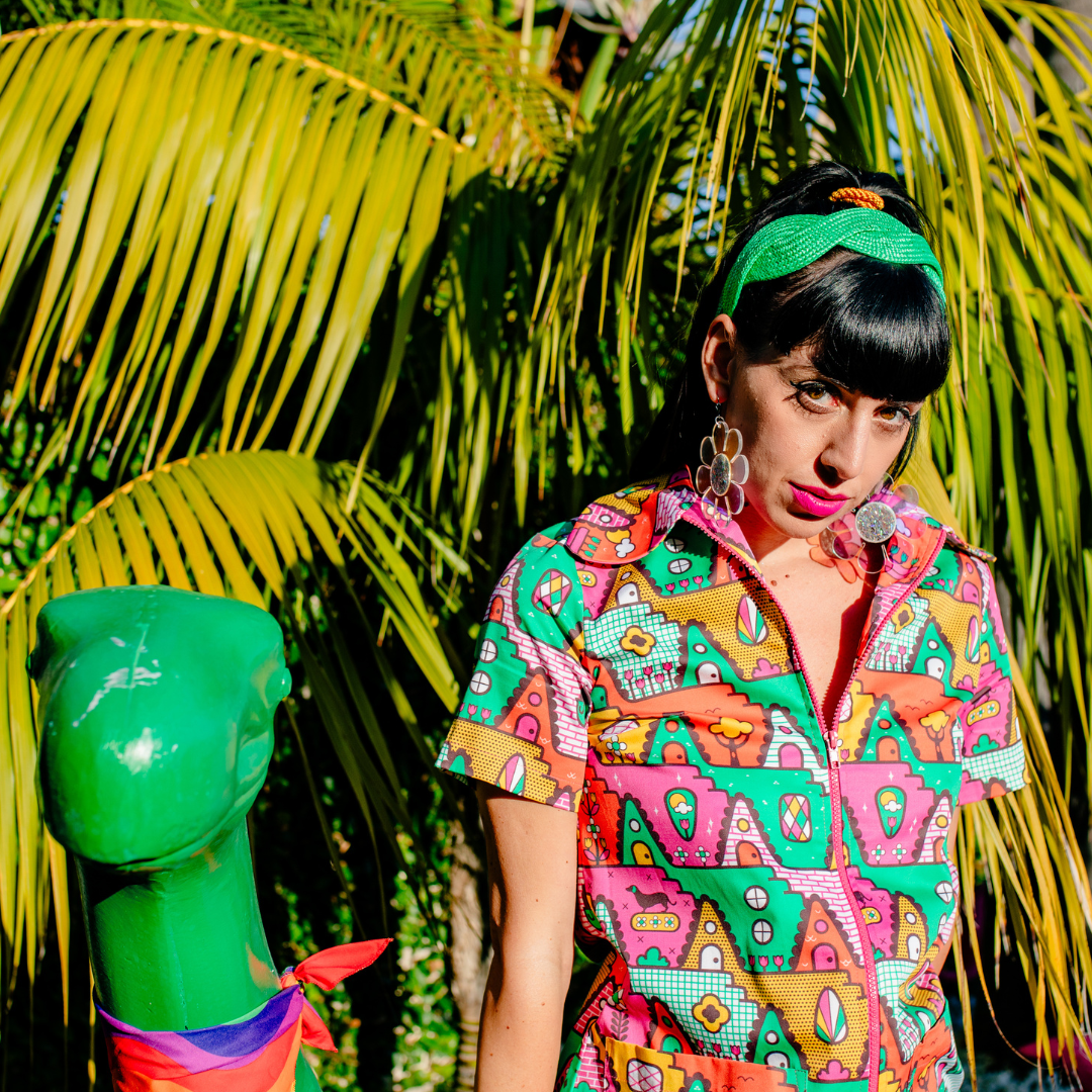 Closeup of dark-haired model in bright yellow, orange, pink and green geometric print jumpsuit