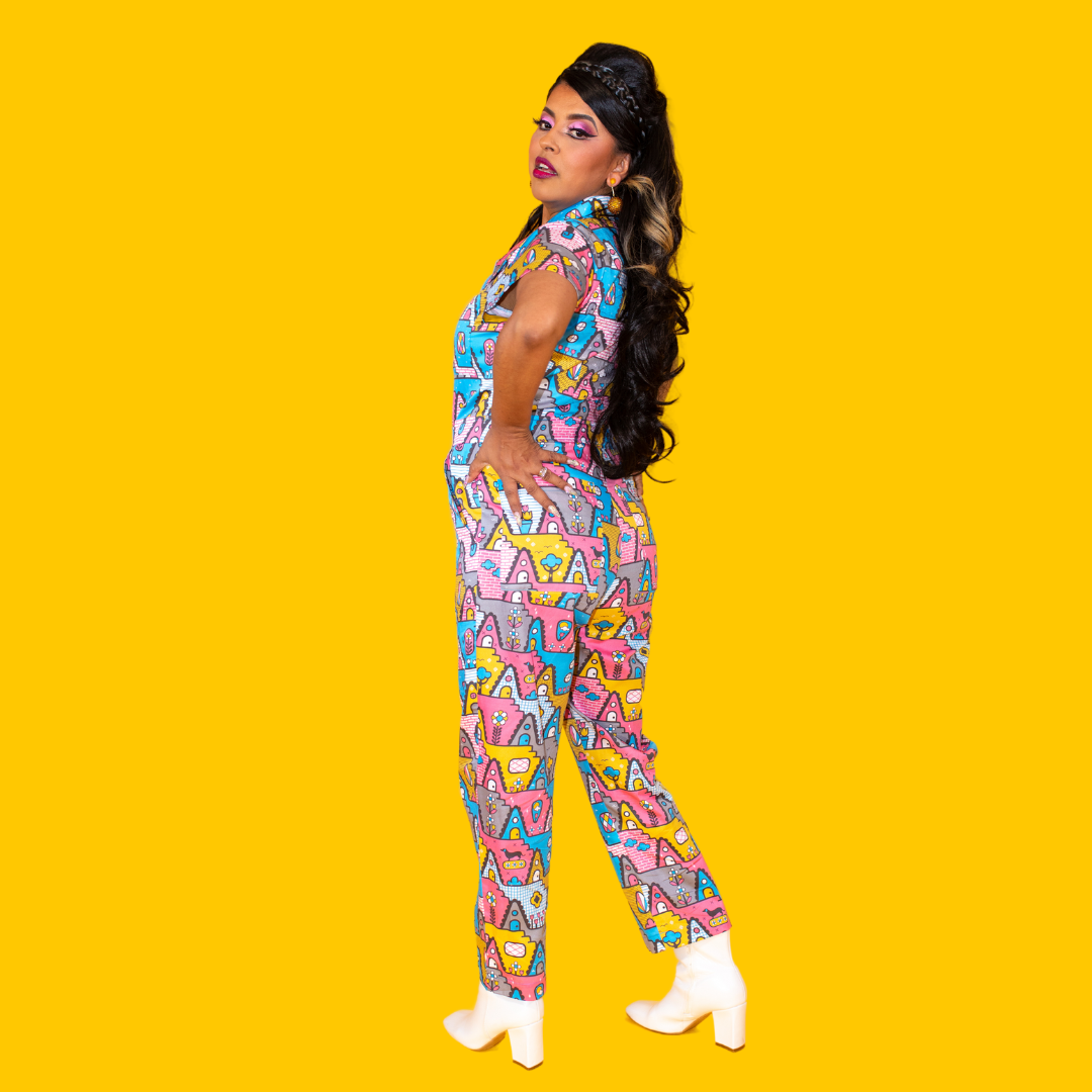 Back view of Latina model with long hair and pastel geometric print jumpsuit and boots