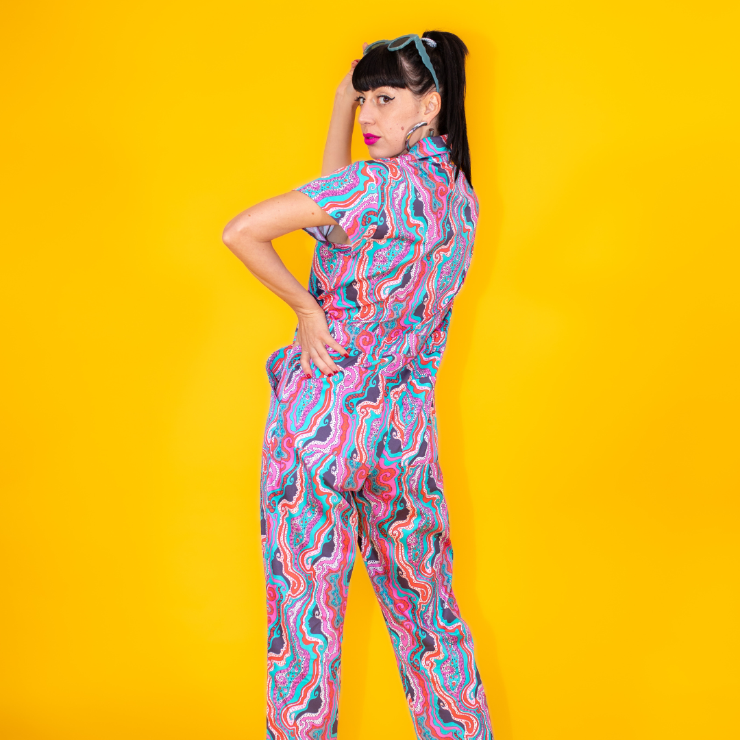 Back view of dark-haired model in psychedelic print jumpsuit