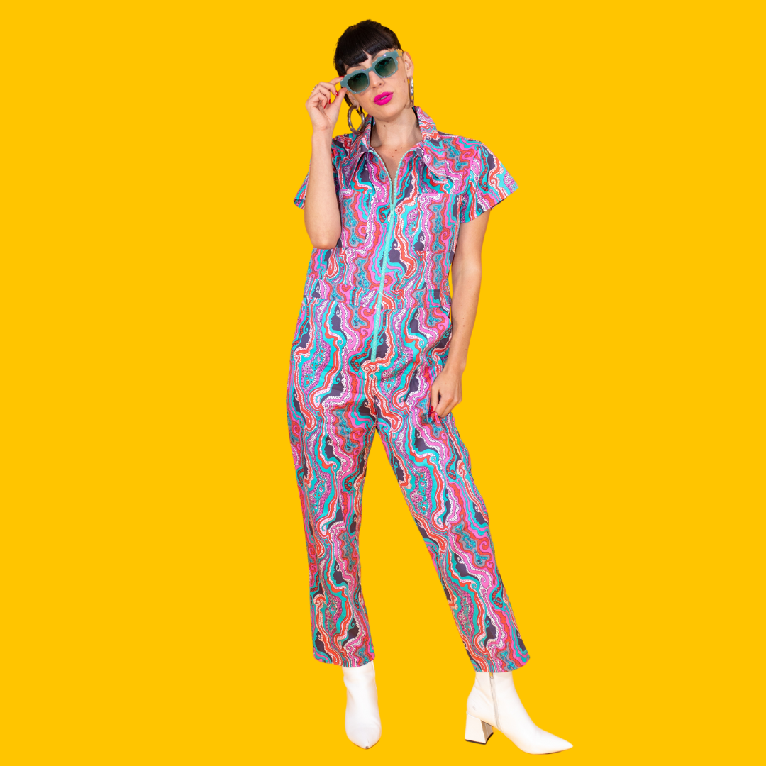 Model in sunglasses, pink lipstick and groovy psychedelic jumpsuit and white boots