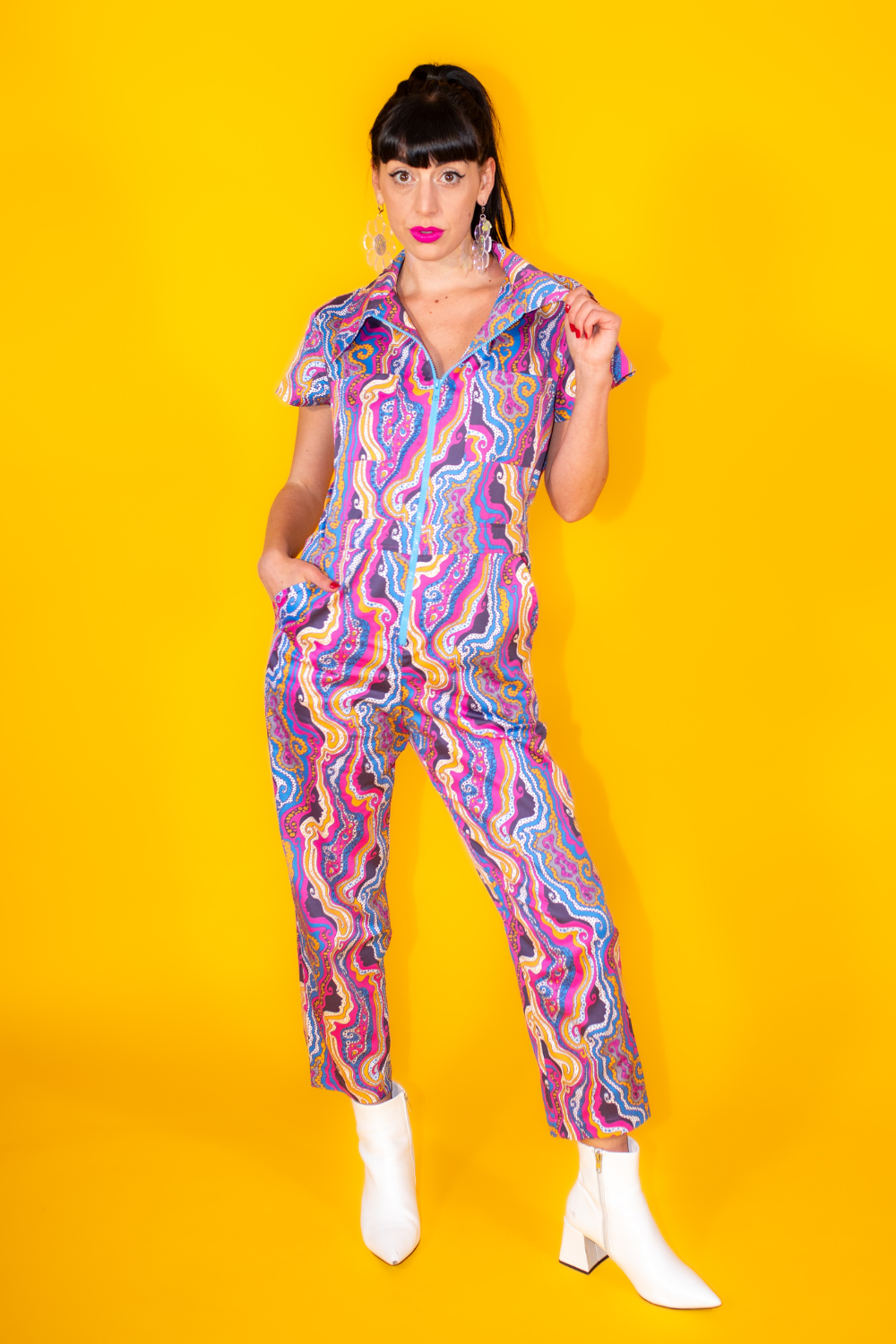 Dark-haired model in bright lipstick and bold psychedelic print jumpsuit