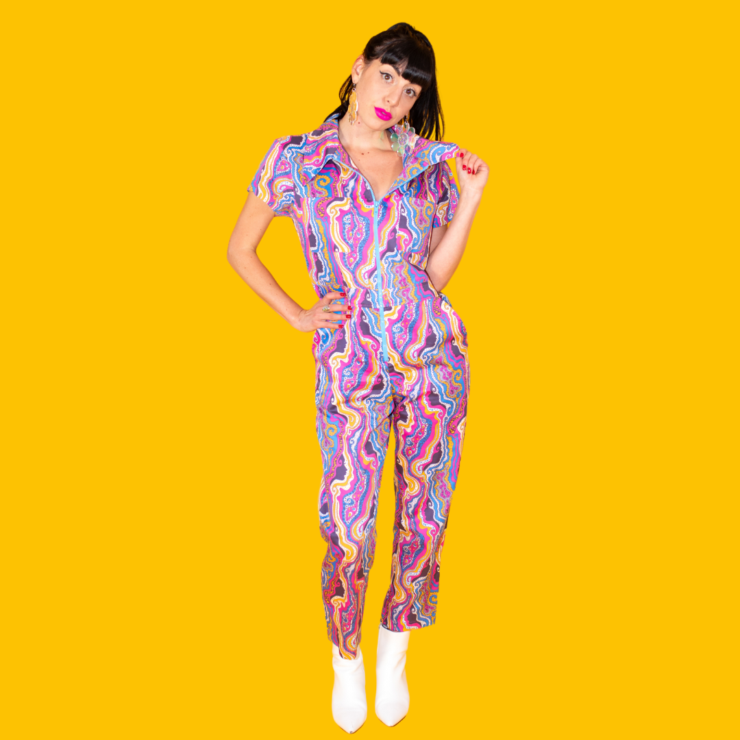 Dark-haired model in bright lipstick and bold psychedelic print jumpsuit