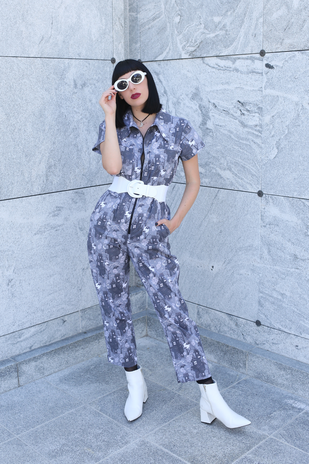 Tall model wearing grey spooky print jumpsuit with white accessories