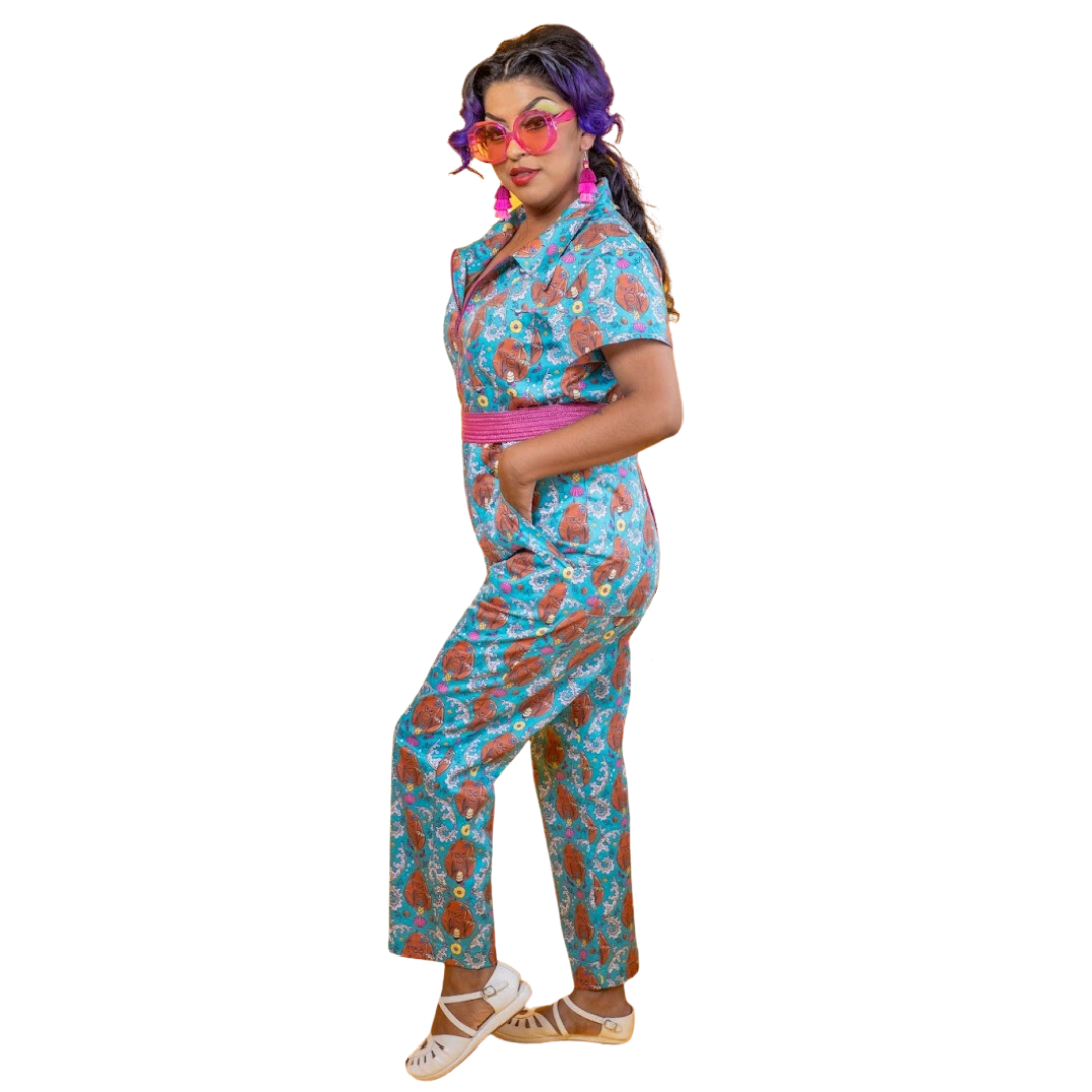 Side view of model in teal tiki monkey print jumpsuit with pineapples