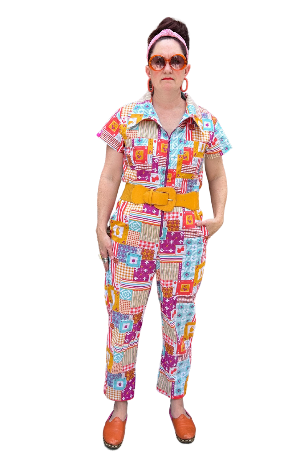 Model wearing sunglasses and patchwork print zip-front collared jumpsuit with belt