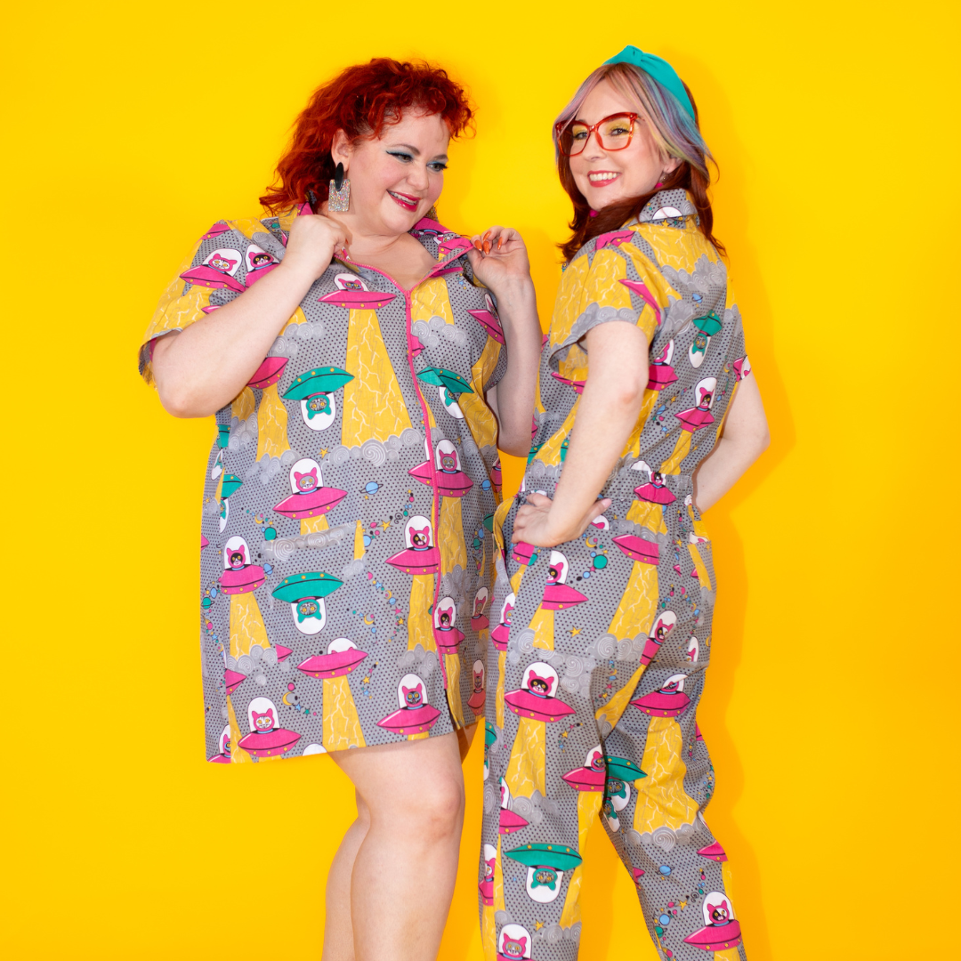 2 models in grey jumpsuits with prints of cats in spaceships