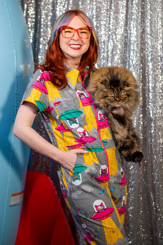 Smiling girl in glasses wearing jumpsuit with a print of cats in spaceships