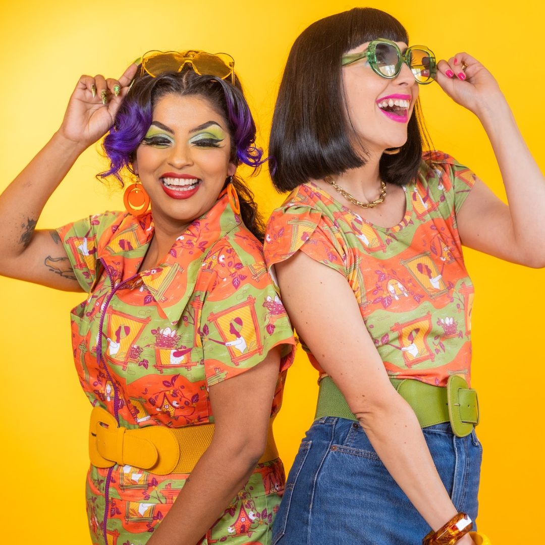 Two laughing models wearing fun orange and green styled outfits 