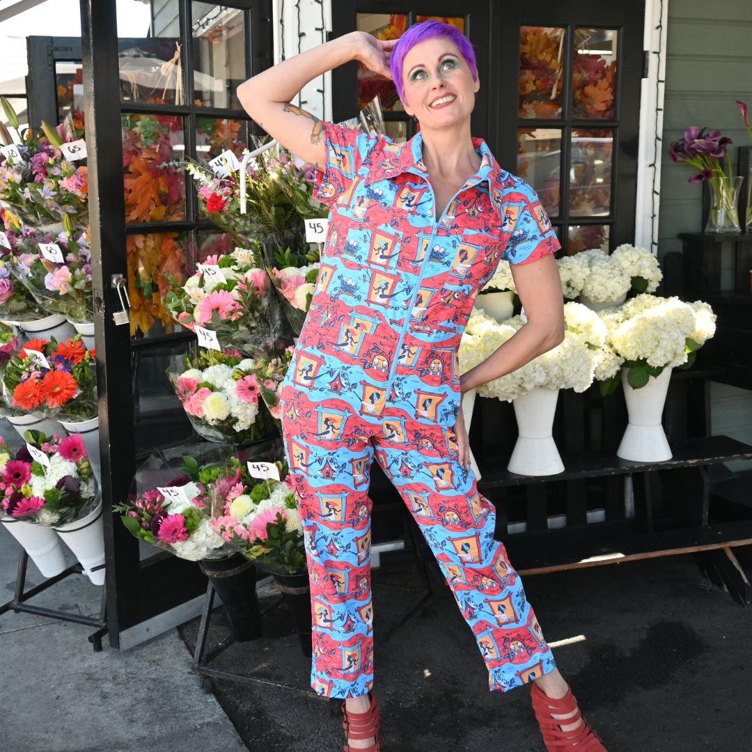 Purple-haired model in red, yellow and blue jumpsuit with girls in windows print