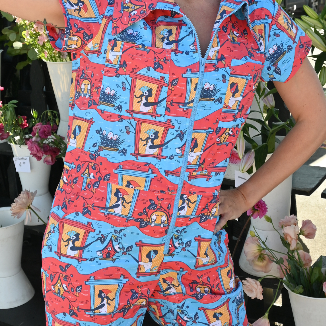 Closeup of red, yellow and blue jumpsuit with girls in windows print