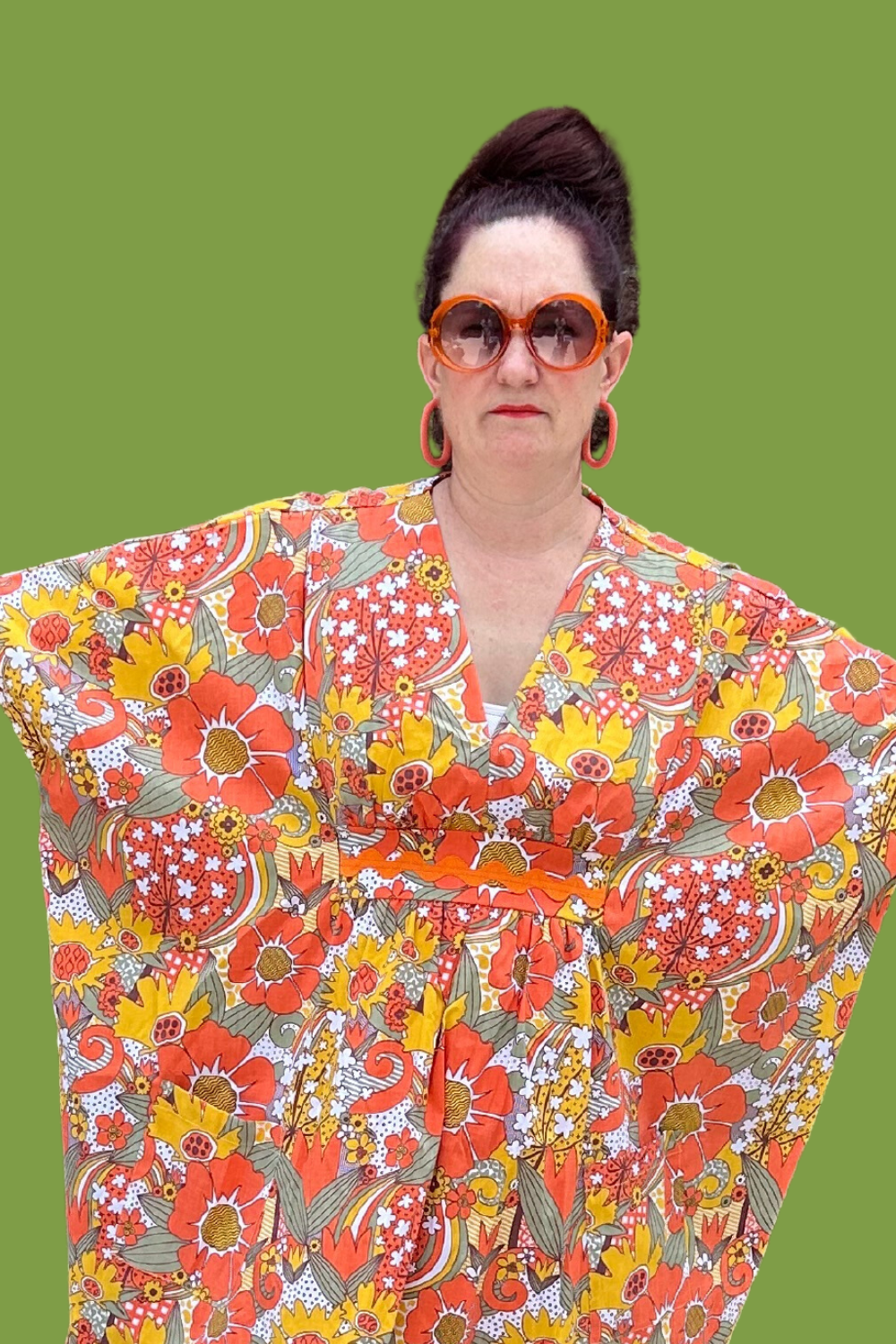 Brown-haired model wearing sunglasses and bright floral print caftan 