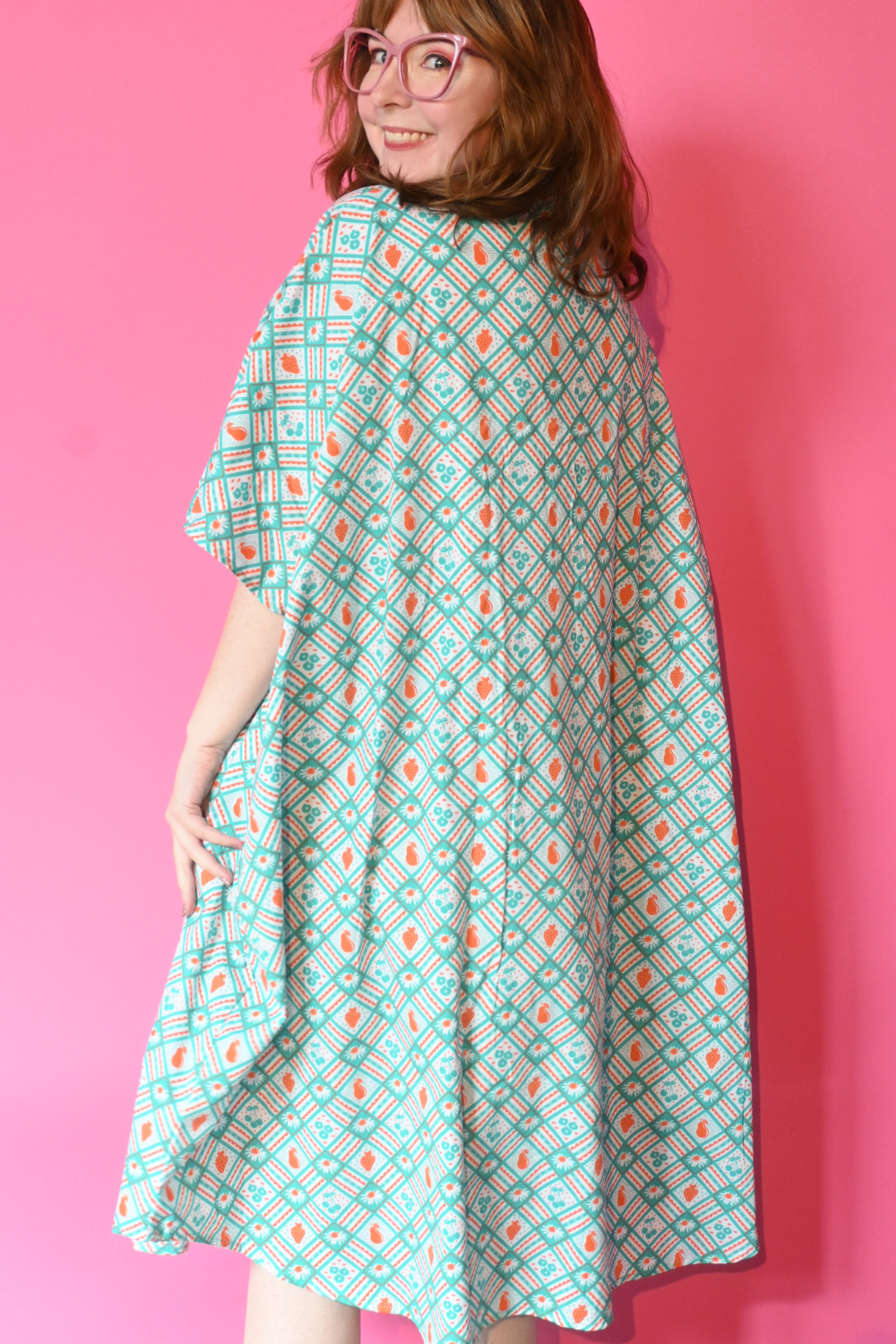 Back of Caftan dress in teal and orange featuring graphic of fruit and flowers