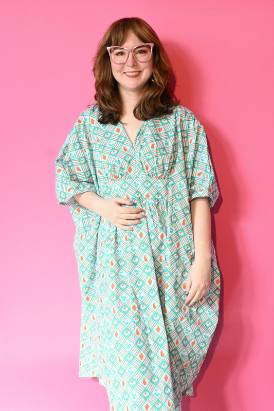 Caftan dress in teal and orange featuring graphic of fruit and flowers