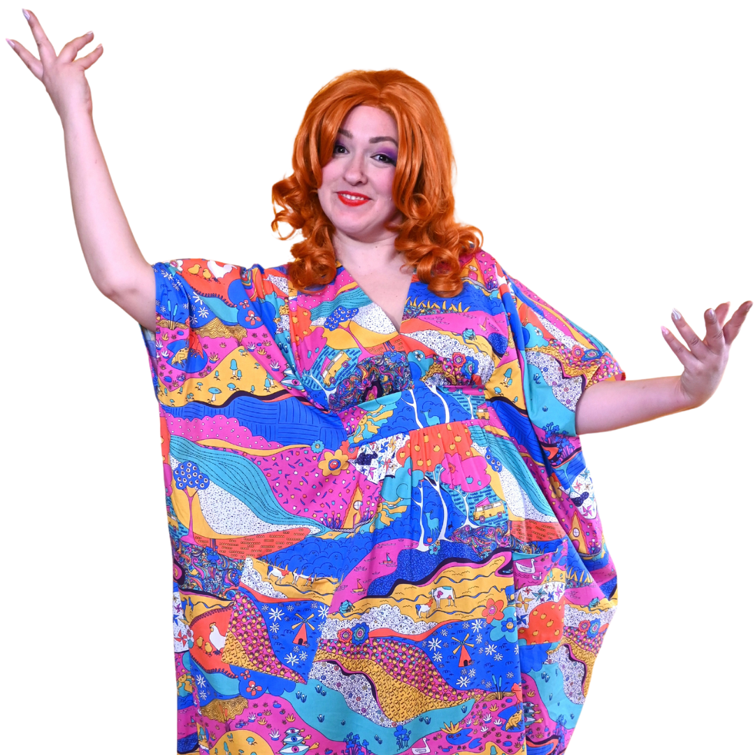 Red-haired model posing playfully in colorful landscape print caftan