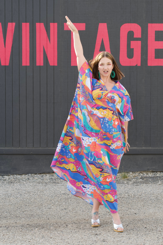 Pretty model in colorful printed caftan in front of Vintage sign