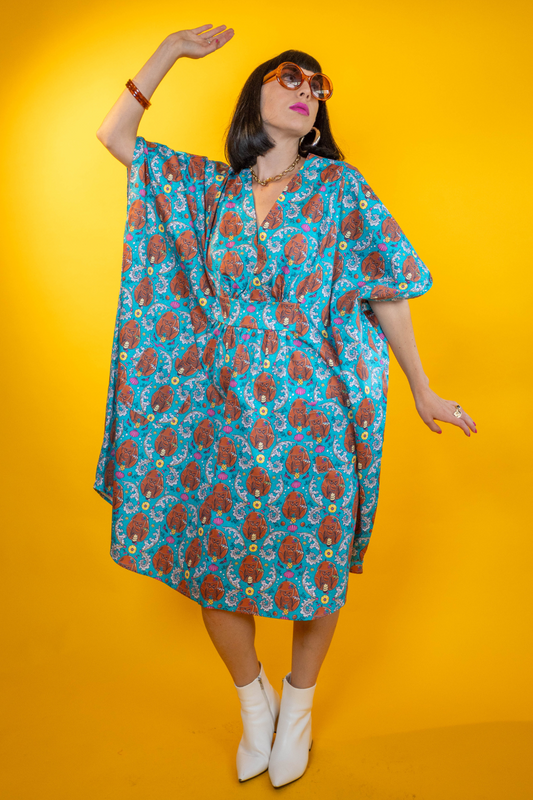 Black-haired model in teal monkey caftan and ankle boots