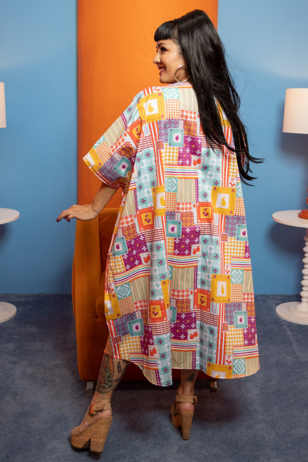 Back view of dark haired model wearing a colorful dress with a patchwork design