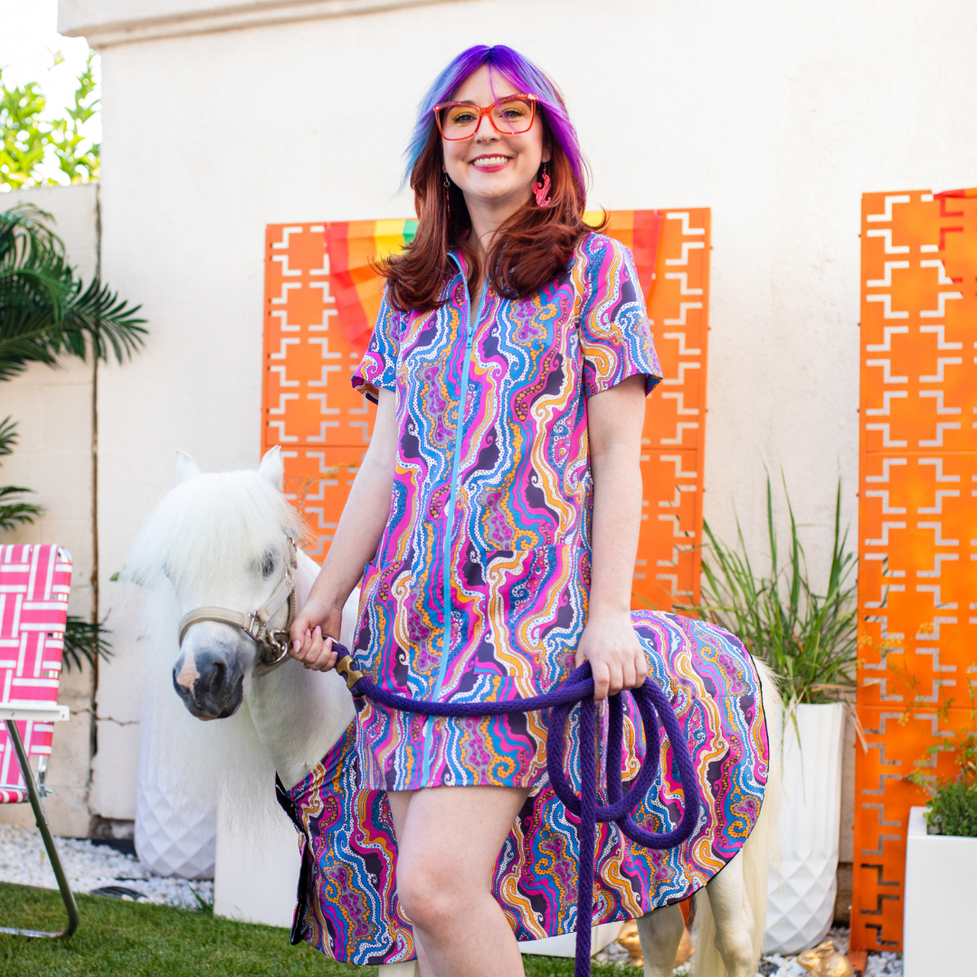 Pretty girl wearing glasses and bright psychedelic print minidress with mini horse