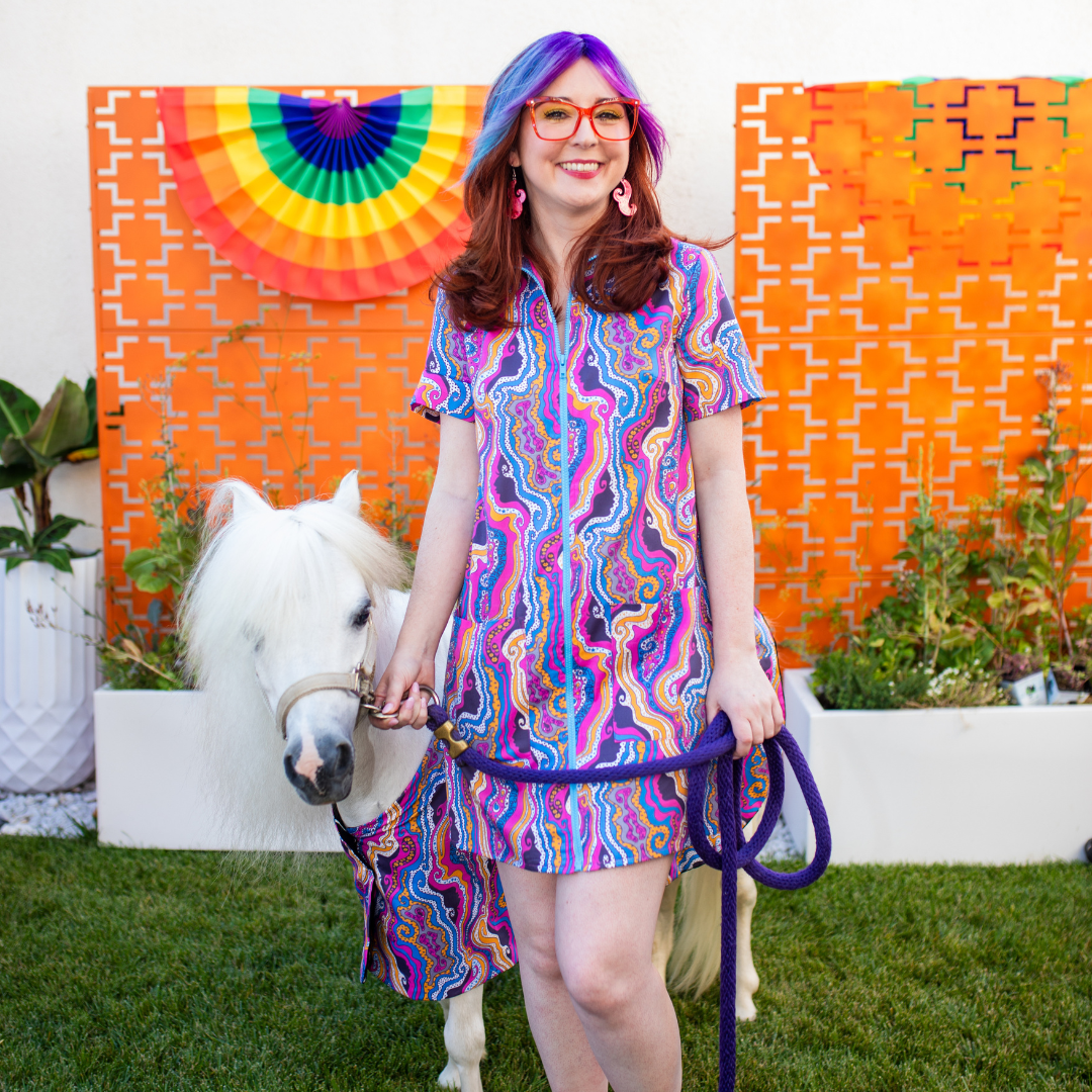 Purple-haired girl wearing psychedelic purple zip-front minidress with mini horse