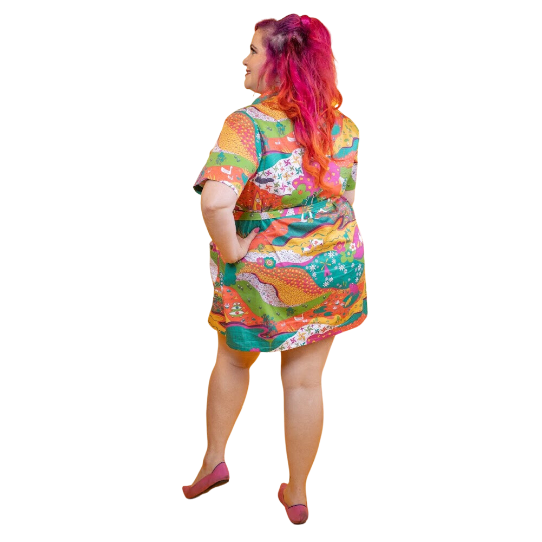 Back view of pink-haired model in brightly colored printed belted minidress 