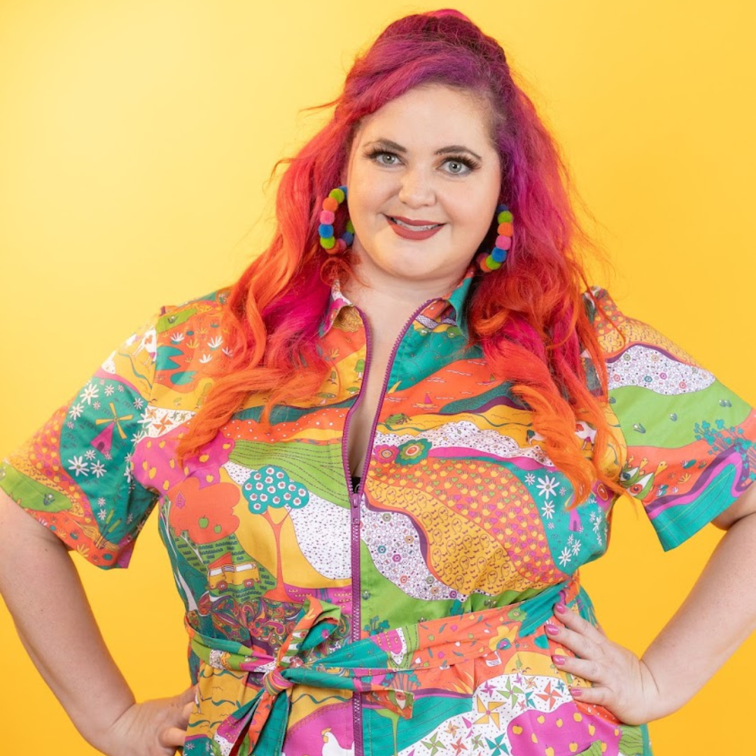 Pink-haired model in brightly colored printed belted minidress 