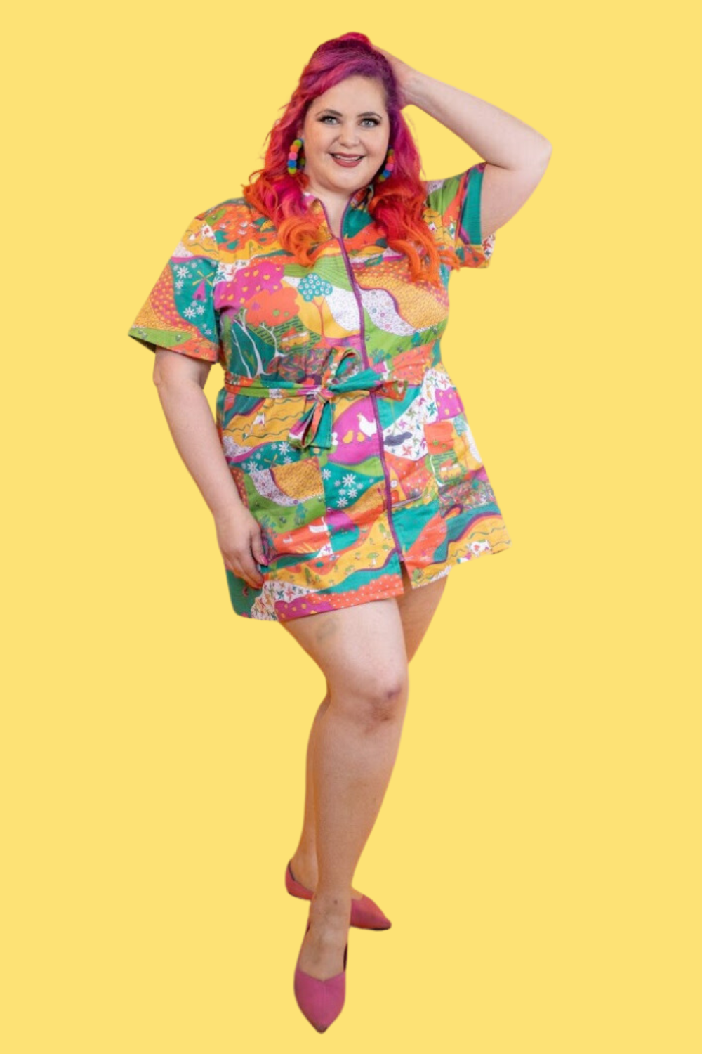 Pink-haired model in brightly colored printed belted minidress 