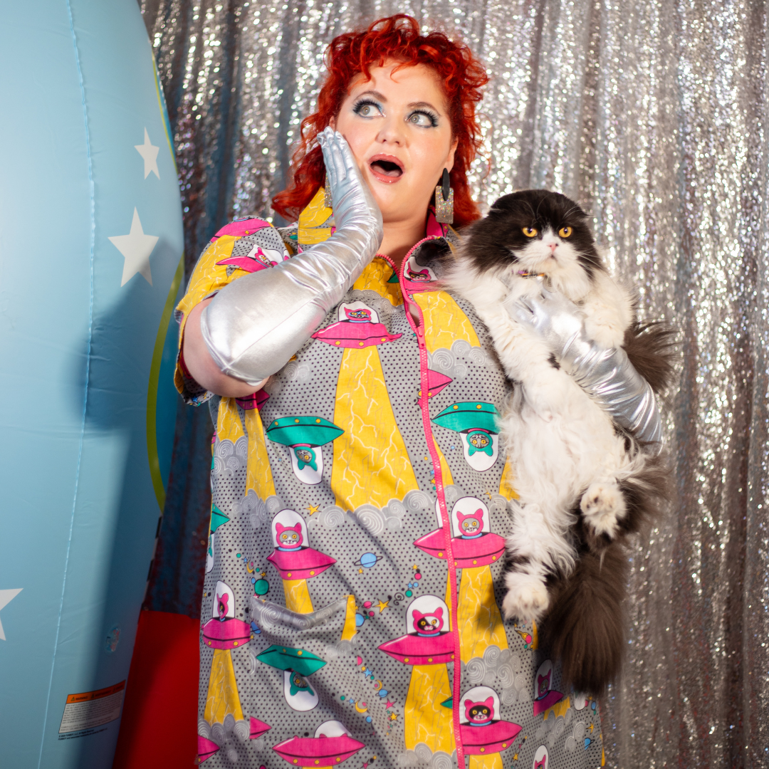 Red-haired model in grey minidress with print of cats in spaceships