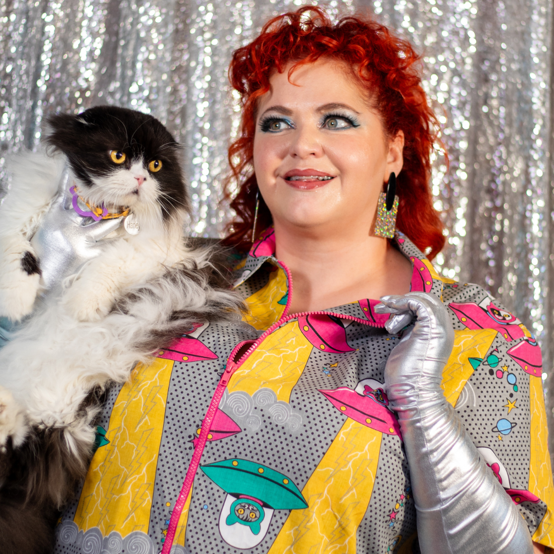 Closeup of model holding cat and wearing dress with space cat print 