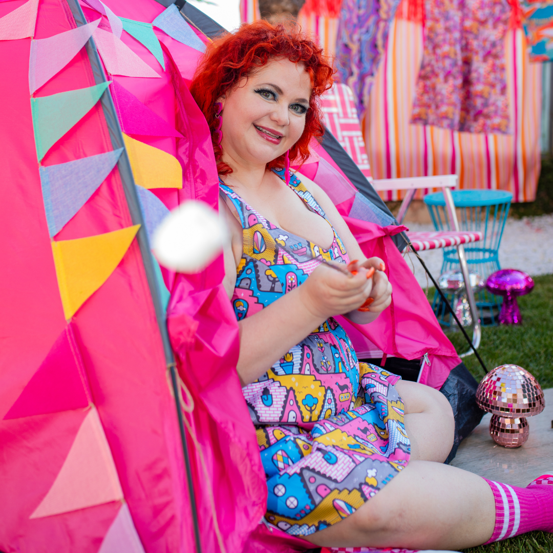 Red-haired model in quirky geometric print dress and peeping out of tent