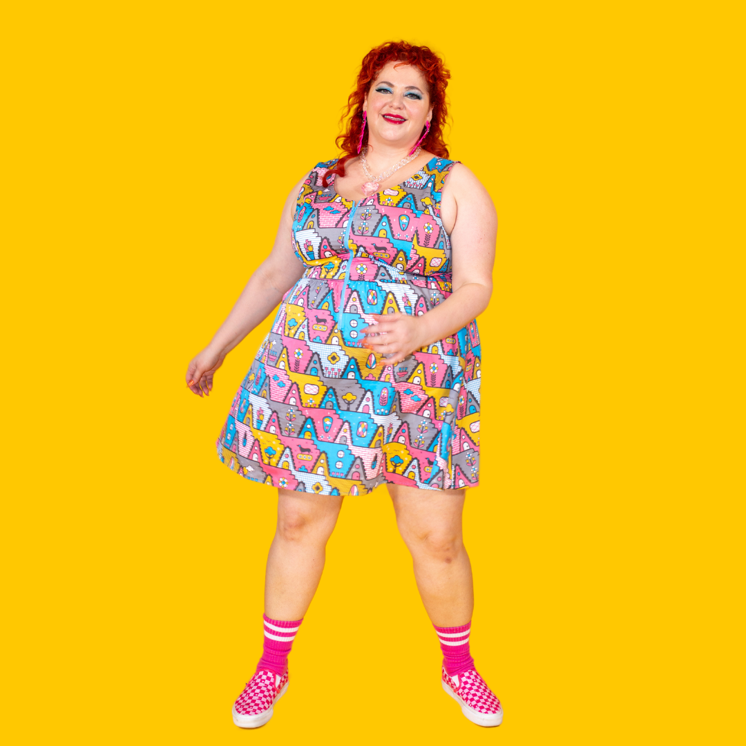 Plus sized red-haired model wearing quirky, fun sleeveless dress in a fun geometric pring