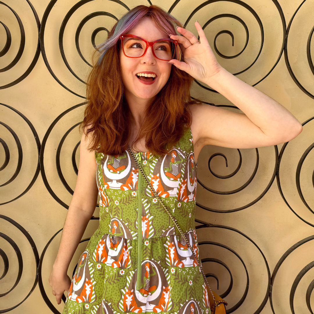 Closeup of model in olive green dress with reading girls, foxes and egg chairs