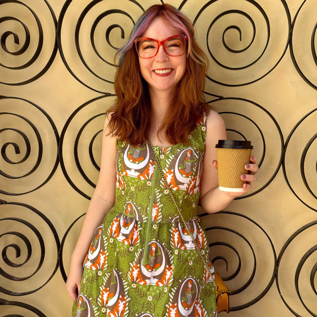 Model holding coffee  in olive green dress with reading girls, foxes and egg chairs