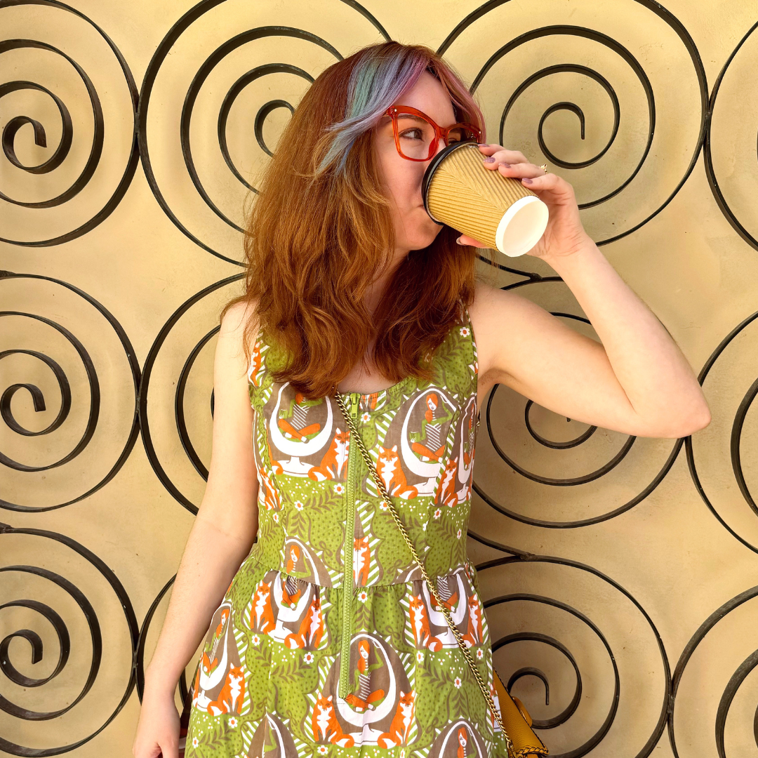 Cute model drinking coffee and wearing olive green printed zip-front dress