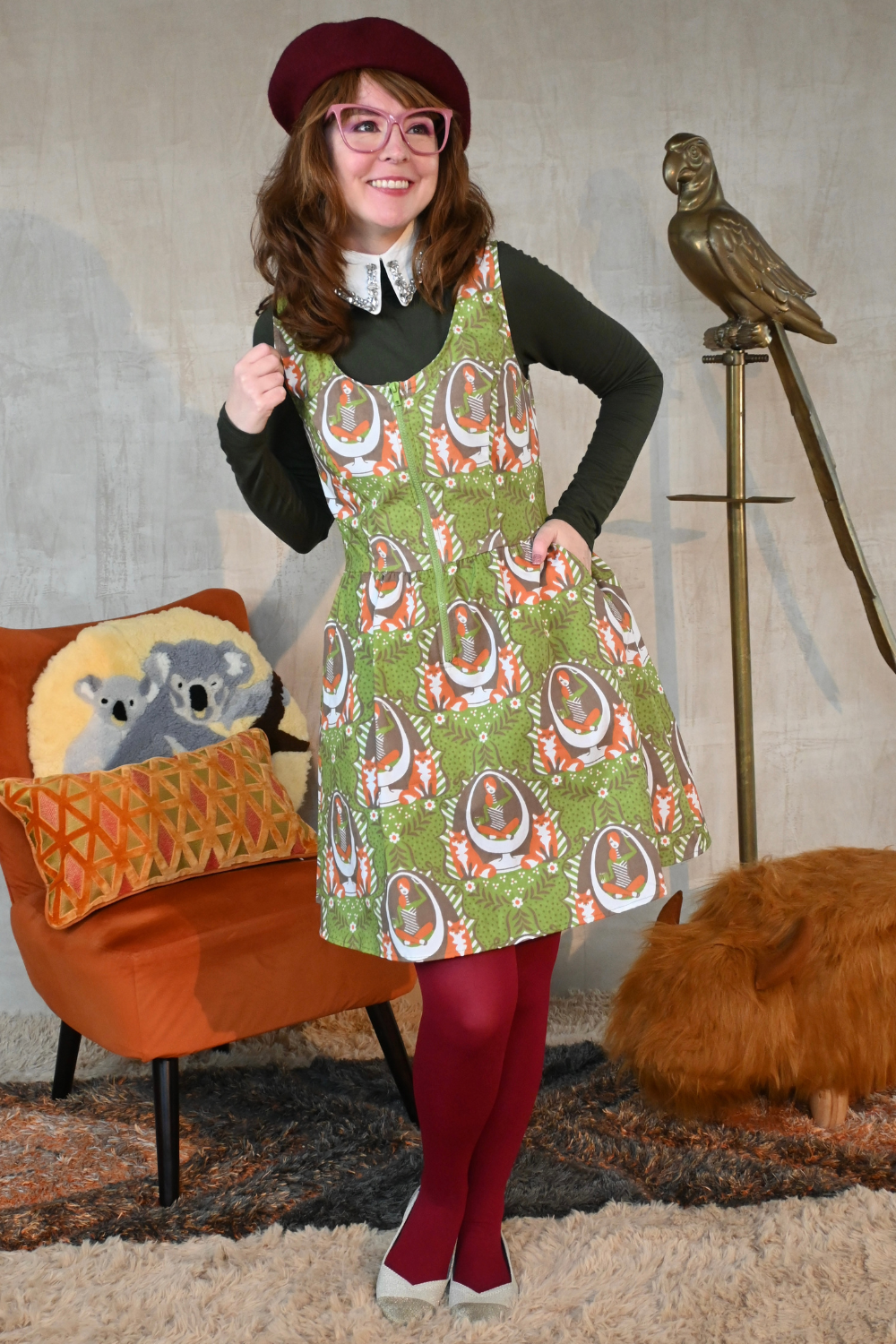 Cute girl wearing beret and green cotton zip-front dress in quirky fox print, accessorized with beret,  sweater, collar, and tights