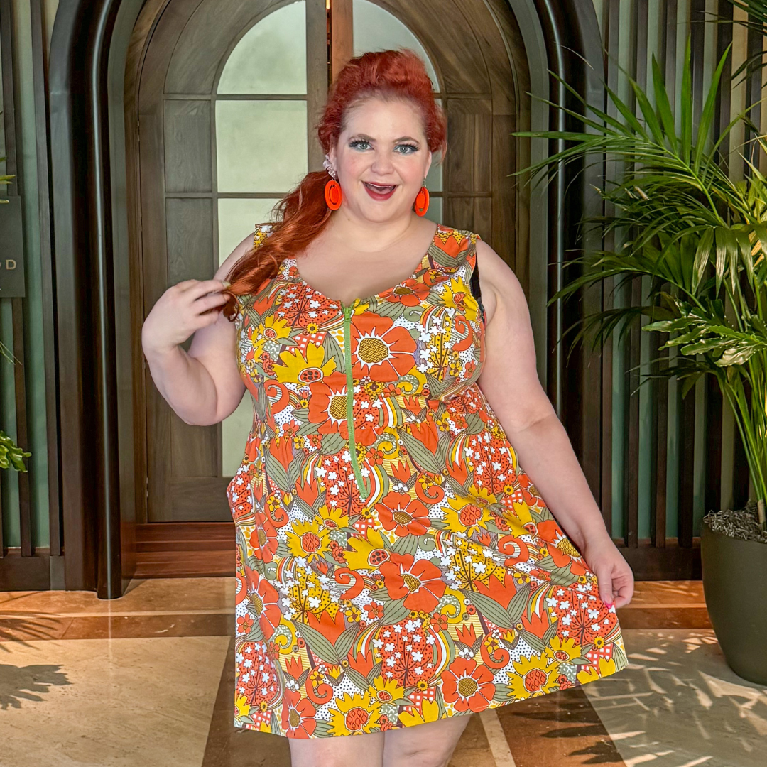 Closeup of red-haired model in brightly colored flower print zip-front dress