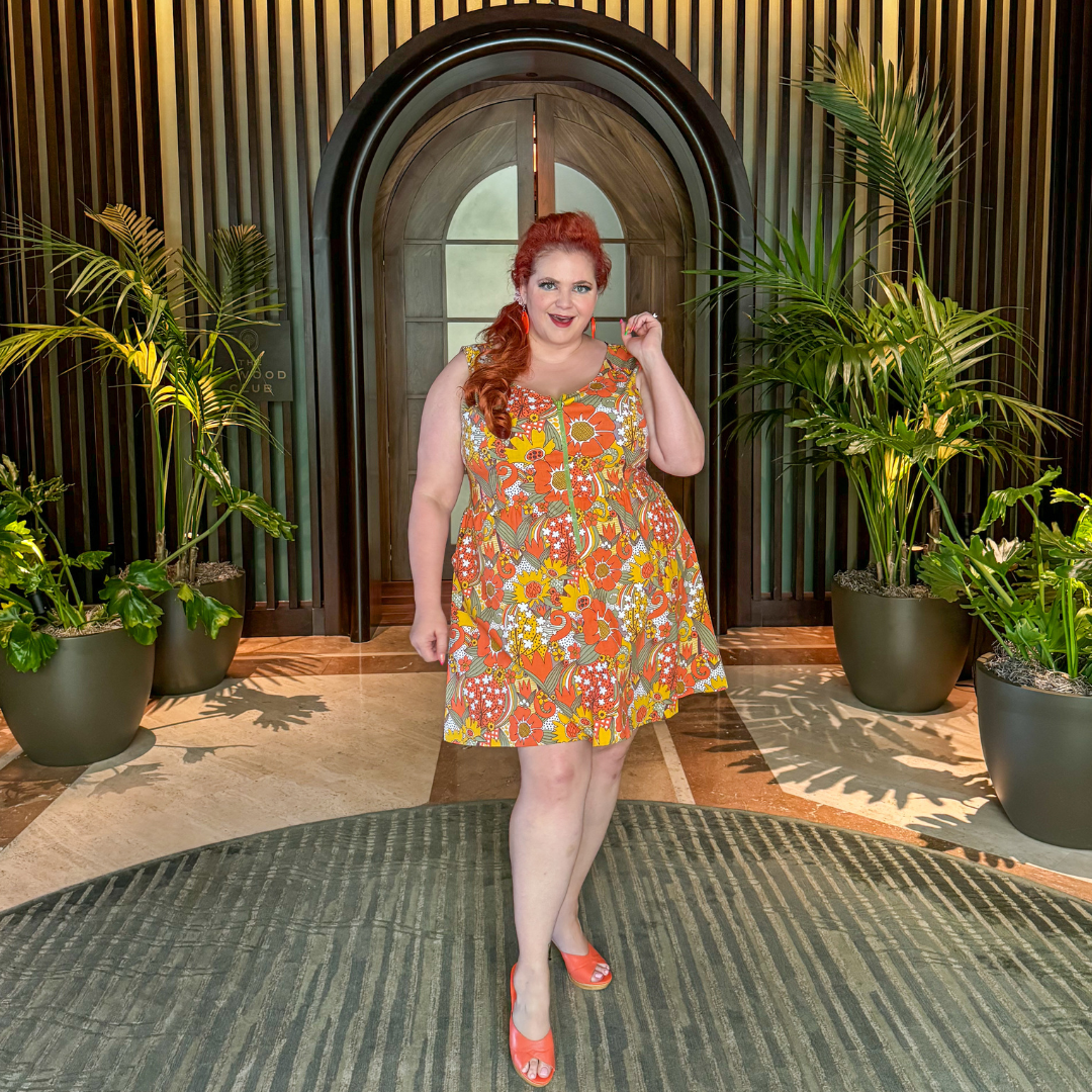 Sassy red haired model in flower print minidress surrounded by potted plants