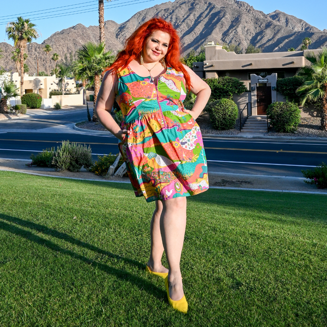 Red-haired model wearing brightly colored zip-front sundress with Palm Springs background