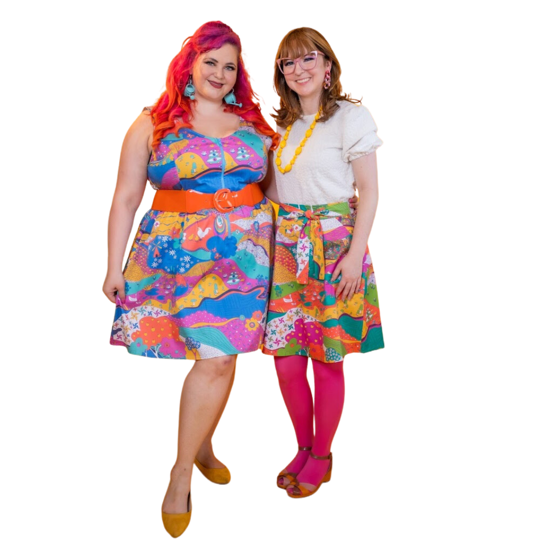 2 models smiling and wearing colorful landscape print clothing