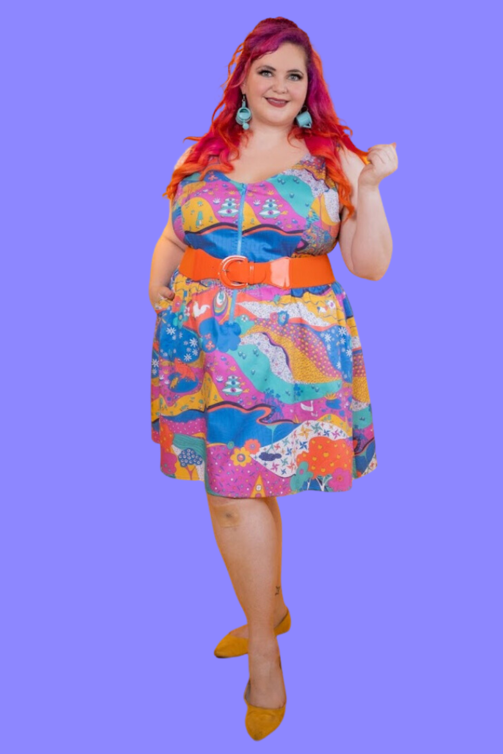 Red-haired model in brightly colored scoopneck dress with retro print and fun earrings