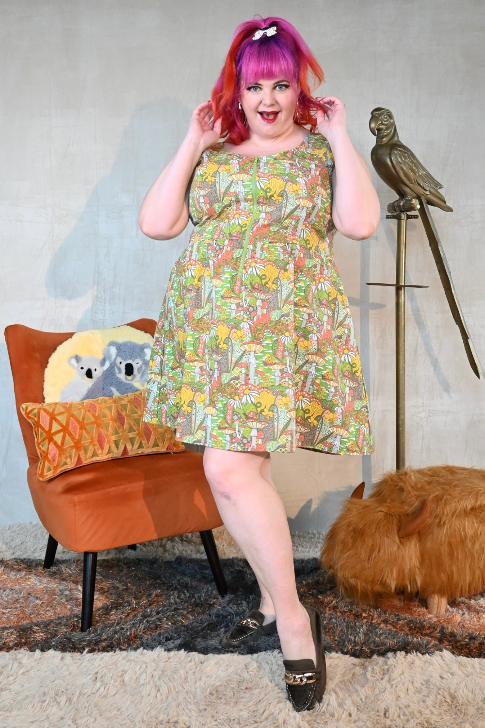 Pink-haired model in olive, yellow and orange mushroom print zip-front midi dress