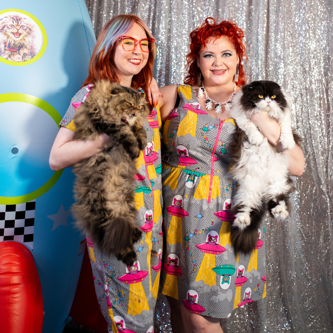 2 fun models wearing clothing featuring cats in space ships and holding cats