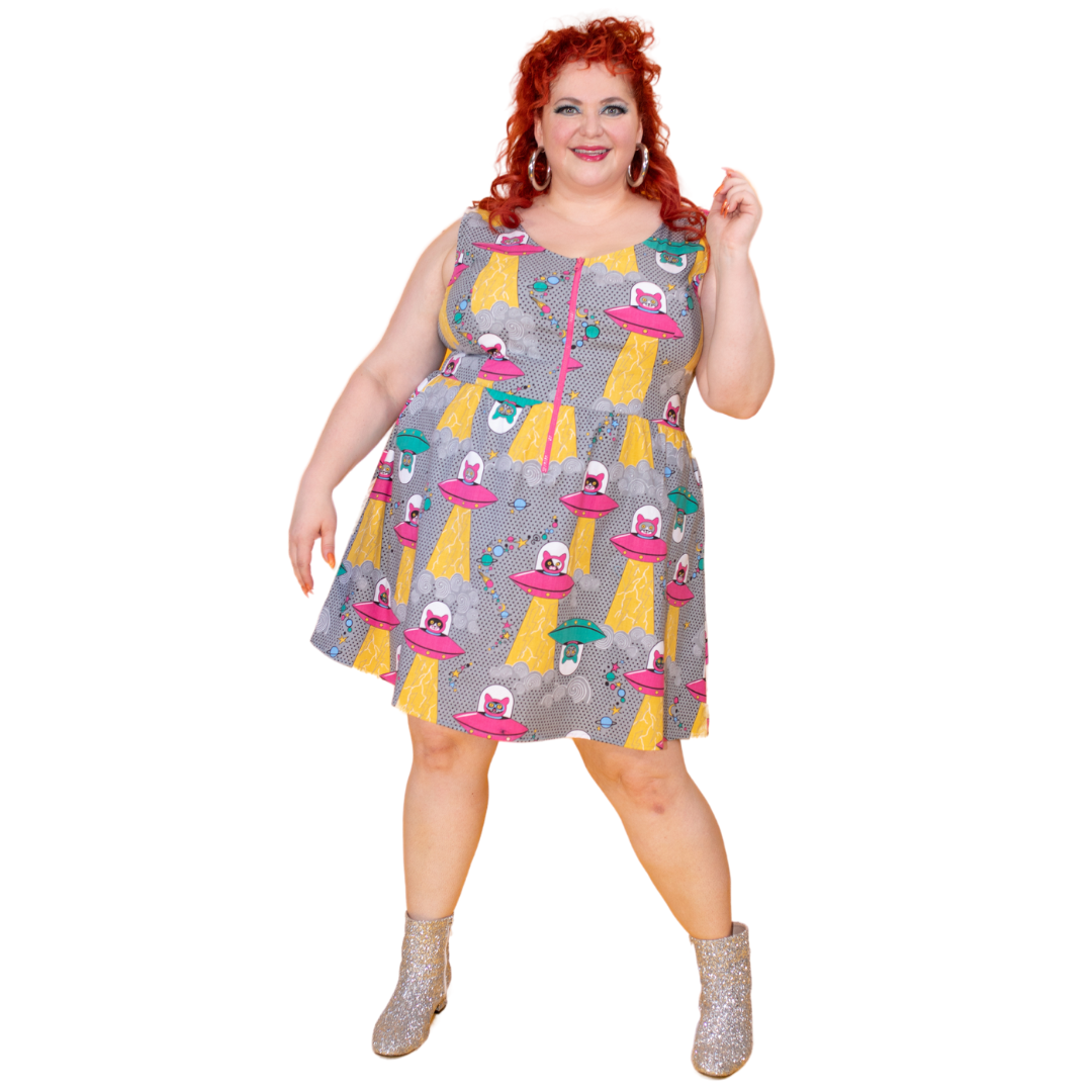 Red-haired model wearing sleeveless dress featuring print of cats in spaceships